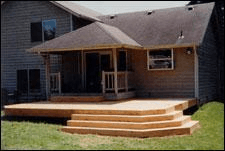 A flat deck with wrapping corner steps built onto the back of a sided home.
